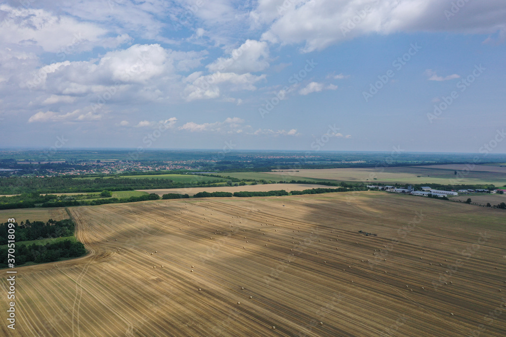 Agricultural field made of yellow round round big bales after harvest, straw rolls, straw bales in the agricultural field. Hay collection in the summer field. Drone photo in Úri, Hungary - 03/07/2020