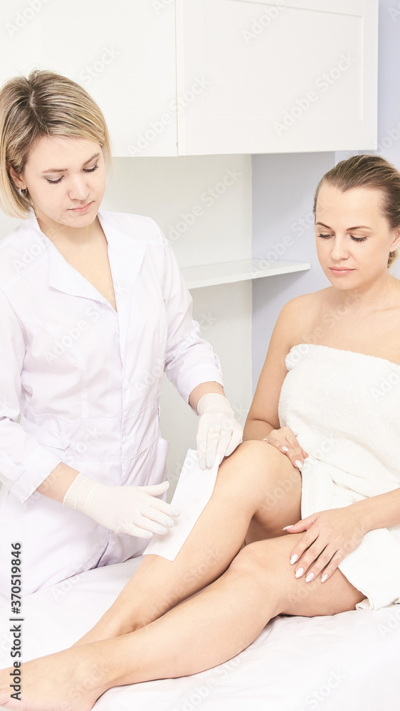 Hot hair removal depilation. Female skin routine. Sugar bodycare. Wax correction. Professional cosmetologist help girl. Sugaring bodycare cosmetics. Leg epilation. Vertical epilation process Hot hair removal depilation. Female skin routine. Sugar bodycare. Wax correction. Professional cosmetologist help girl. Sugaring bodycare cosmetics. Leg epilation. Vertical epilation process