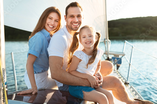 Family Of Three Relaxing On Yacht Hugging Sitting On Deck © Prostock-studio