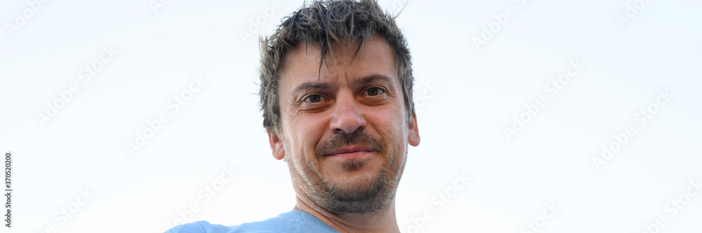 Fototapeta premium portrait of a happy young 30+ years old man tourist, unshaven and shaggy, against the sky, view from below. banner