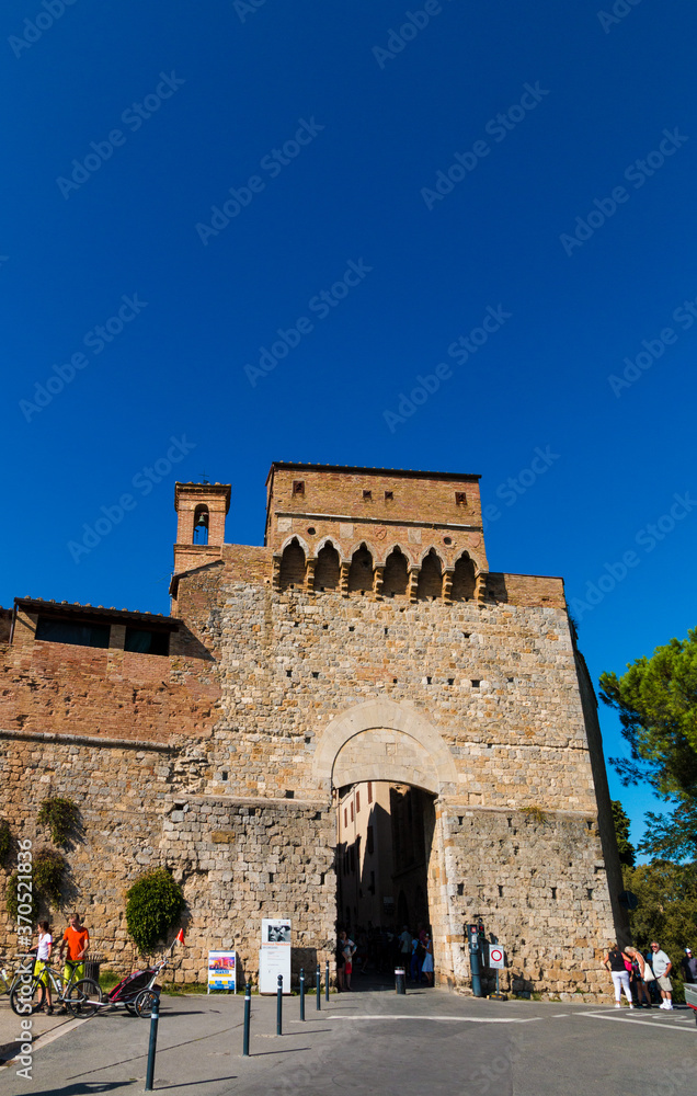 Nice portrait shot of the gate San Giovanni, the entrance of the walled medieval town San Gimignano in Tuscany, Italy. A church bell tower from a demolished church is still visible from the outside.