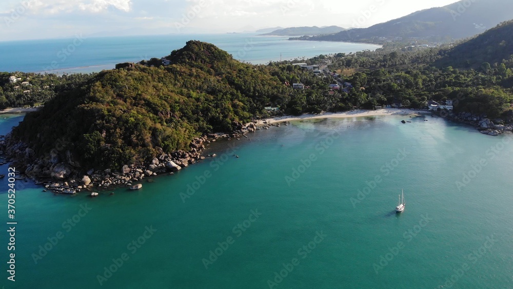 Boat near tropical shore. Amazing drone view of modern yacht sailing on calm sea water near coast of tropical volcanic island. Exotic Paradise Koh Samui, Silver Beach.