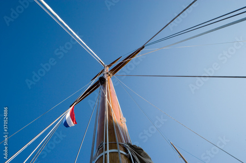 Deck of a classic wooden sailing yacht. Netherlands. Mast and ropes. Dutch flag.