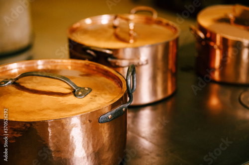 Three copper pots with closed lids on a metal surface.