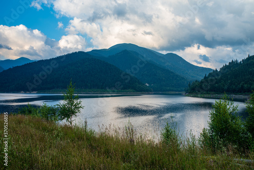 Gura Apei lake with Godeanu mountain range on the background in Romania