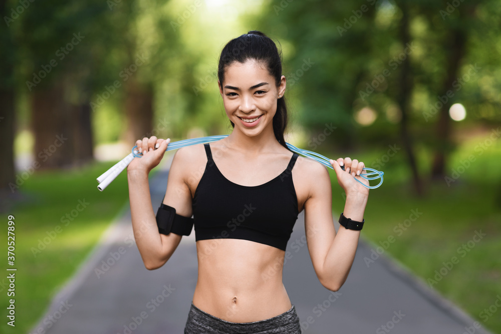 Cardio Training Outdoors. Positive Asian Girl Holding Skipping Rope - obrazy, fototapety, plakaty 