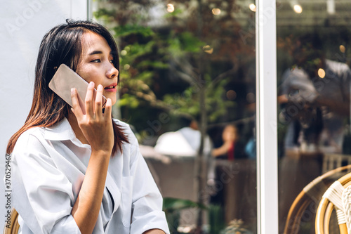 Portrait of smiling happy beautiful asian woman relaxing using digital smartphone.Young asian girl talk with friend at cafe