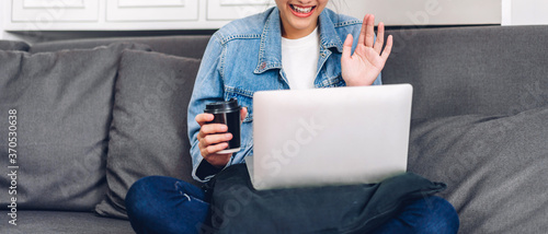Young smiling happy beautiful asian woman relaxing using laptop computer working and video conference meeting at home.Young creative girl say hi and typing on keyboard.work from home concept