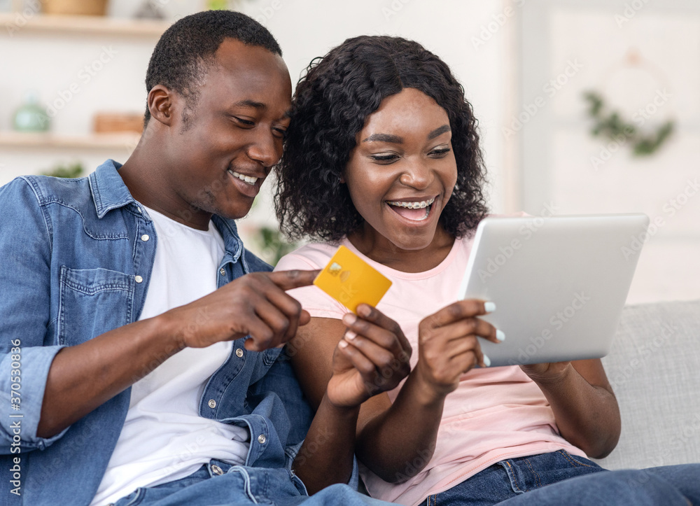 Closeup of black couple making purchases online, holding digital tablet