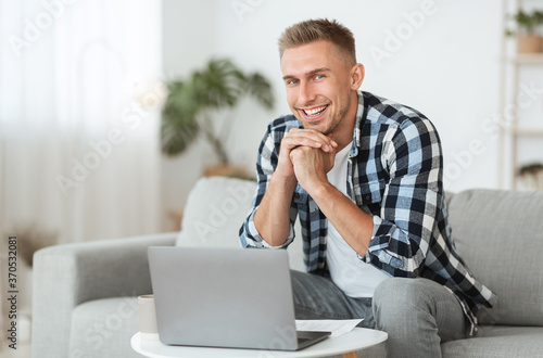 Young man sitting on couch and looking at camera