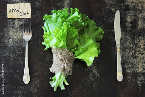 Raw diet concept. Green salad leaves and raw diet lettering.