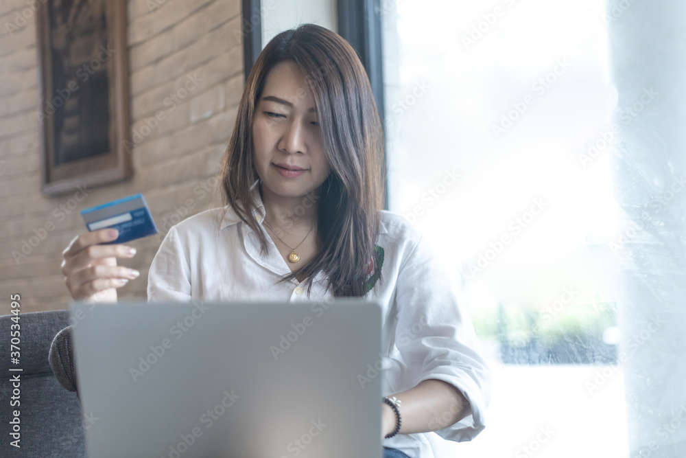 Asian woman using credit card for shopping on laptop. Asian female holding credit card and payment by computer notebook Asian woman using credit card for shopping on laptop. Asian female holding credit card and payment by computer notebook