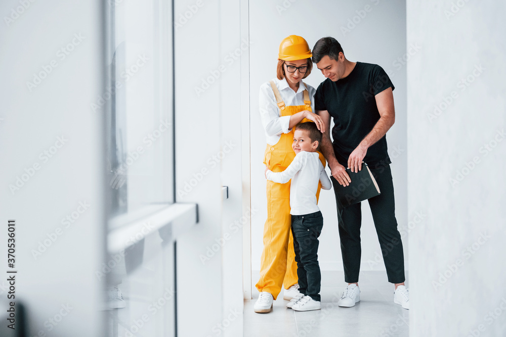 Female worker in yellow uniform standing indoors with man and child Female worker in yellow uniform standing indoors with man and child