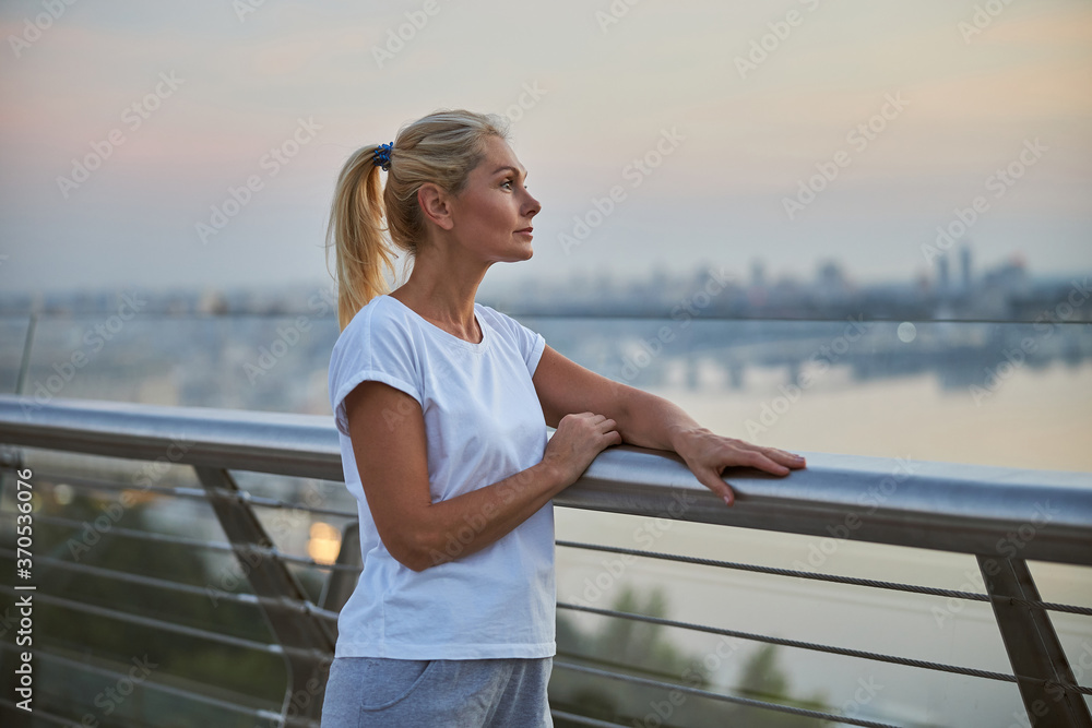 Pensive sporty woman leaning on the railing