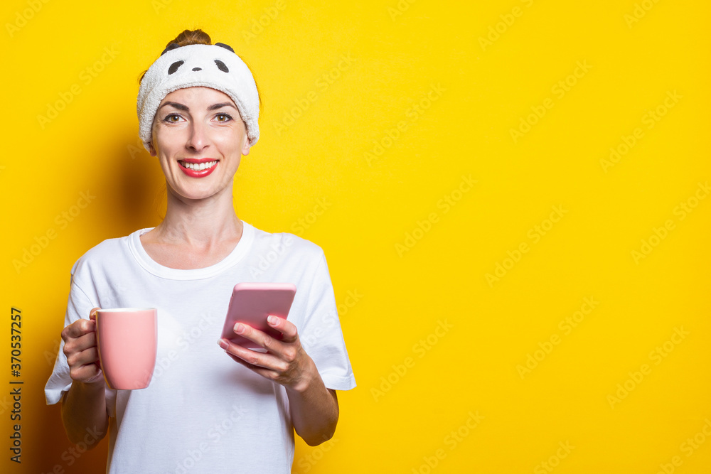 Smiling young woman with a phone and a cup of coffee on a yellow background Smiling young woman with a phone and a cup of coffee on a yellow background