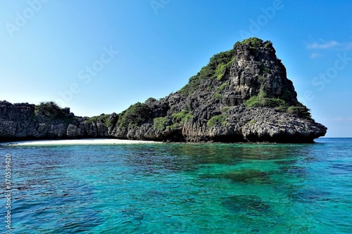 Secluded beach on the island. A semicircular strip of sand is surrounded by a rock. The clear aquamarine sea is calm. There are no people. Silence, relaxation. Thailand