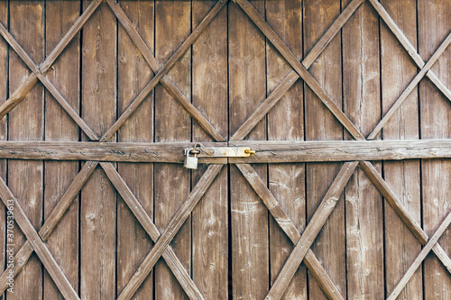 Grunge wooden barn door. Rustic vintage desk construction background. Countryside architecture texture. Village building entrance. Metal padlock for safety reason.