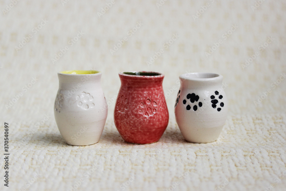 three small pots with cat paws on a beige background. handmade. made on a potter's wheel three small pots with cat paws on a beige background. handmade. made on a potter's wheel