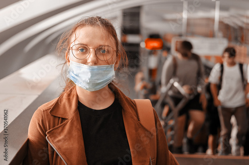 A woman in the wrong medical mask is standing in the subway. The protective mask is not properly worn on the face of a woman in transport