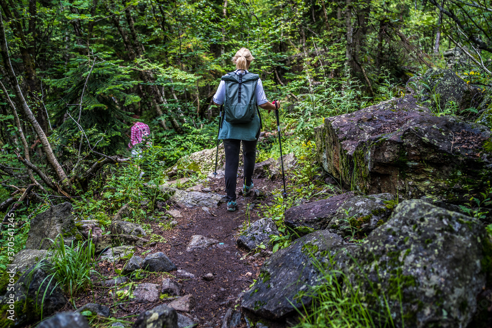 Rear view of woman engaged in nordic walking on rocky path. Rear view of woman engaged in nordic walking on rocky path.