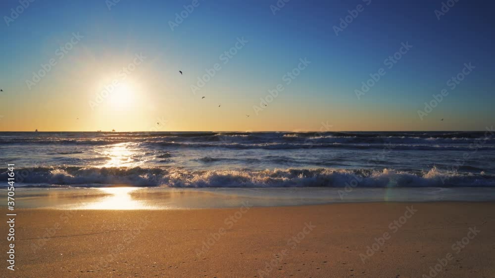 Tropical sunrise on the beach. Summer morning. Waves splashing onto the sand. Tropical sunrise on the beach. Summer morning. Waves splashing onto the sand.
