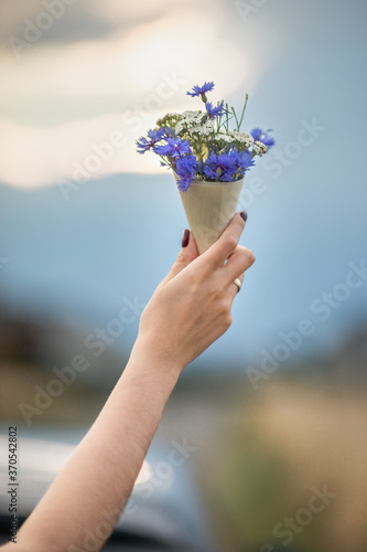 Polne kwiaty w drewnianym rożku, trzymane w dłoni