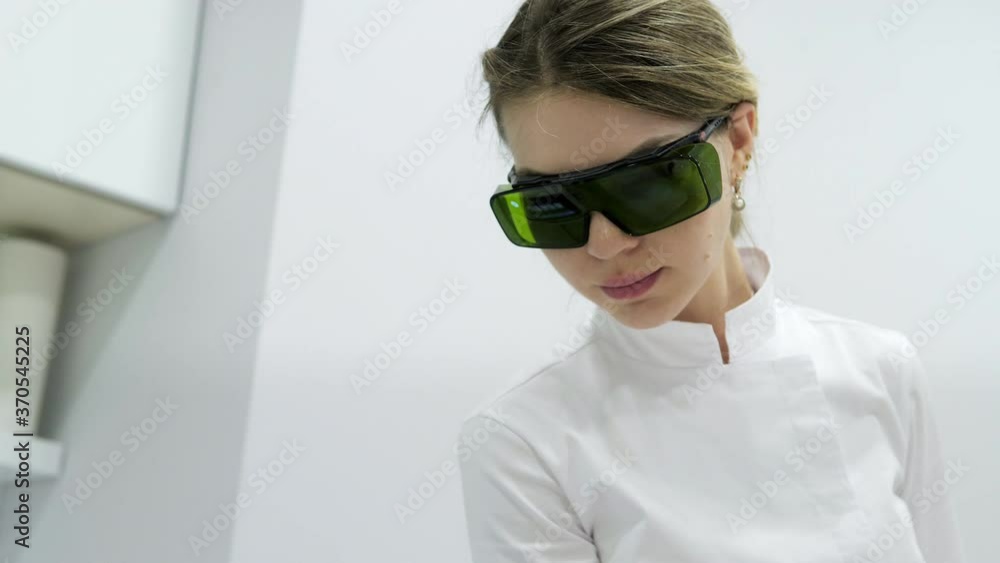 Beautician removes hair on beautiful female legs using a laser. Laser procedure at clinic Beautician removes hair on beautiful female legs using a laser. Laser procedure at clinic