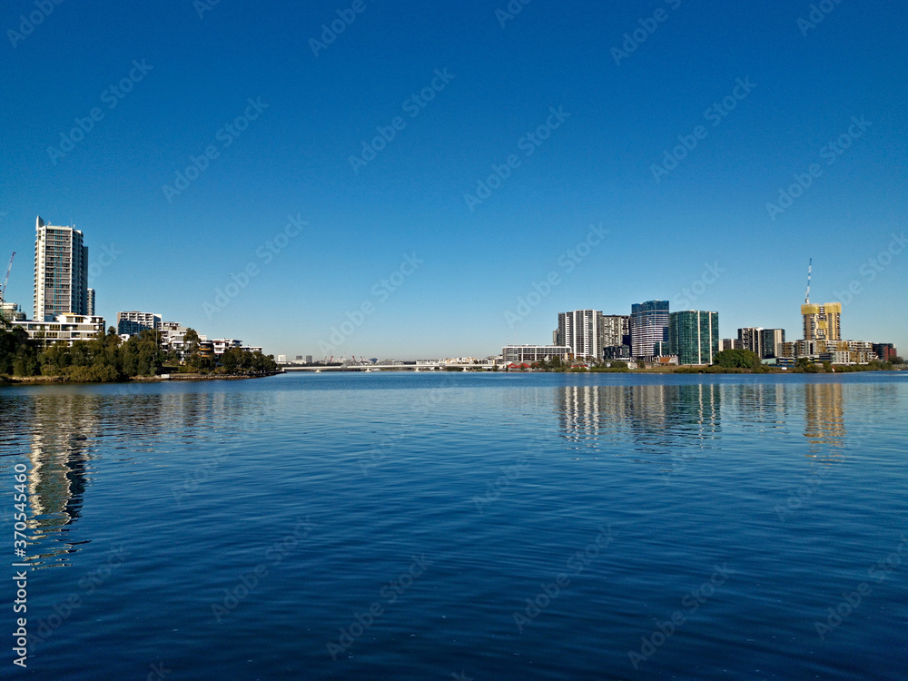 Beautiful view of high-rise buildings on the riverbank on a sunny day with deep blue sky, Parramatta river, Meadowbank, Sydney, New South Wales, Australia