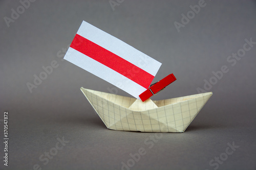 paper boat with the flag of belarus (unofficial) and other flags of neighboring states, russia, poland, europe. photo