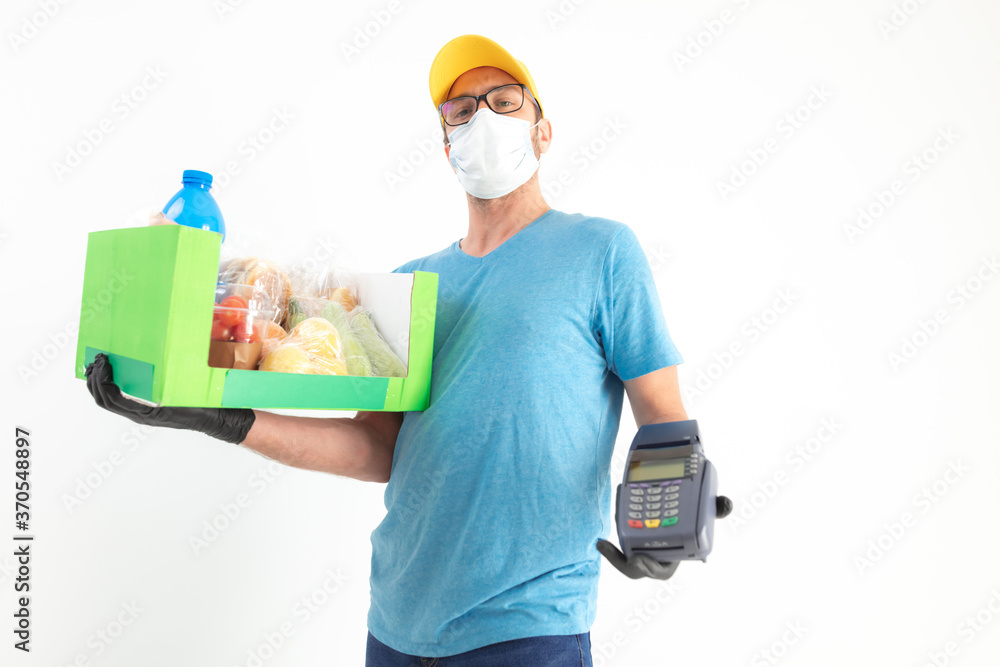 Delivery guy with protective mask holding box / bag with groceries and POS for contactless payment. Delivery guy with protective mask holding box / bag with groceries and POS for contactless payment.