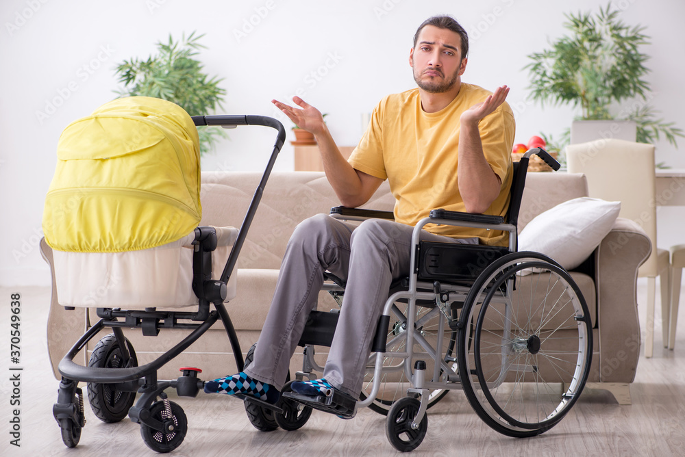 Young man contractor in wheel-chair looking after newborn Young man contractor in wheel-chair looking after newborn