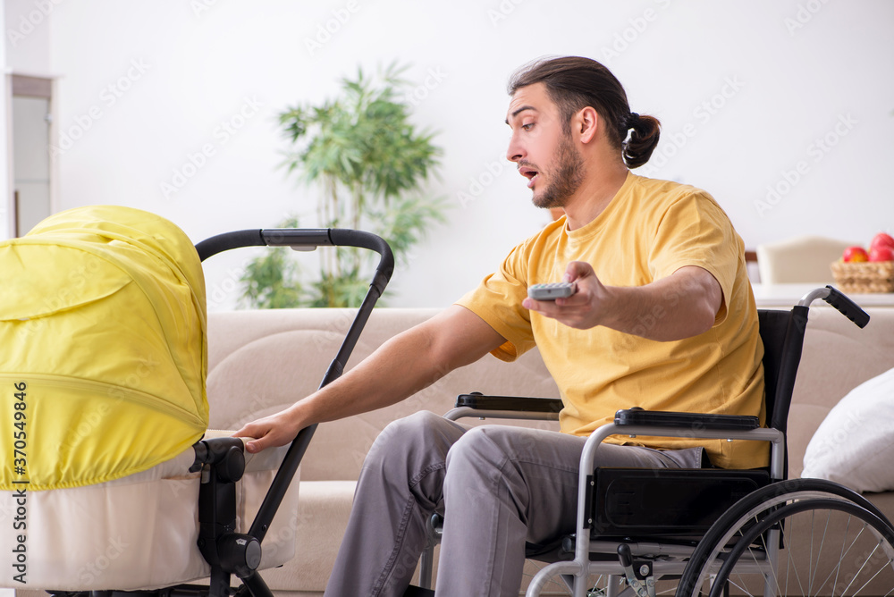 Young man contractor in wheel-chair looking after newborn Young man contractor in wheel-chair looking after newborn