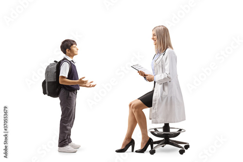 Schoolboy talking to a young female doctor seated on a chair