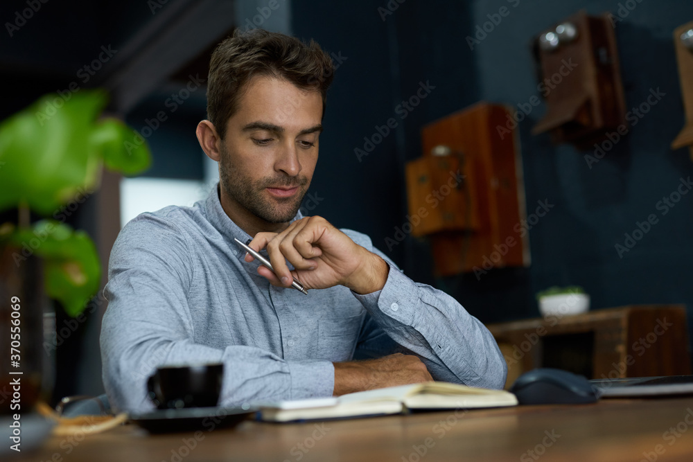Young businessman going over notes while working at his desk Young businessman going over notes while working at his desk