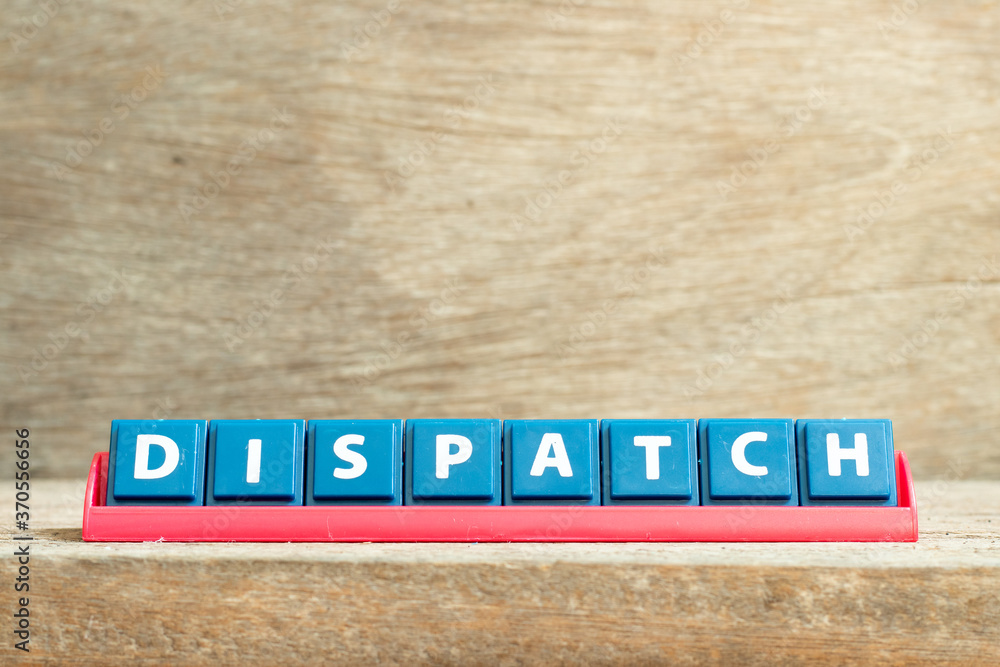 Tile letter on red rack in word dispatch on wood background Tile letter on red rack in word dispatch on wood background
