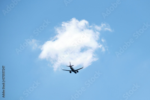From below of aircraft flying with blue and cloudy sky