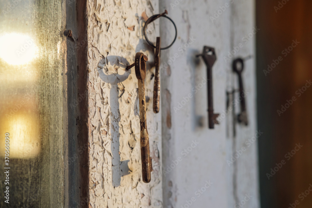 Old rusty key on the wooden door frame with broken white paint with a blurred reflection of a sunset on a dirty glass Old rusty key on the wooden door frame with broken white paint with a blurred reflection of a sunset on a dirty glass
