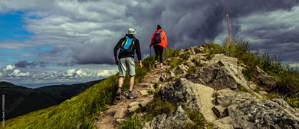 Obraz premium Couple hiking in the mountains. Hiking path in Bieszczady Poland. Rock and stones on hiking trail.