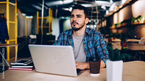 Pensive freelancer working at laptop in cafe