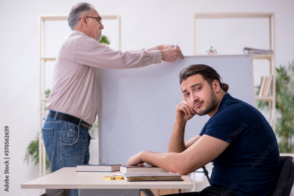Obraz premium Old teacher and young male student in the classroom