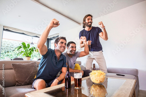 Group of friends watching a game on tv celebrating the victory of their team