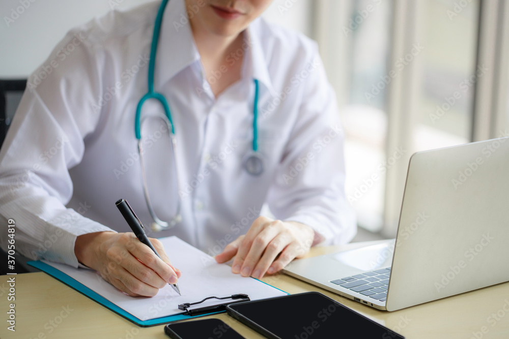 Young Asian male doctor is recording a medical history on the clipboard and explaining something to the female patient. Medical and health care concepts Young Asian male doctor is recording a medical history on the clipboard and explaining something to the female patient. Medical and health care concepts