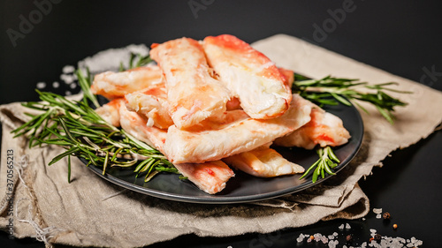 King crab leg meat on a dark plate with spices and herbs. Delicious and healthy traditional seafood. Food banner format