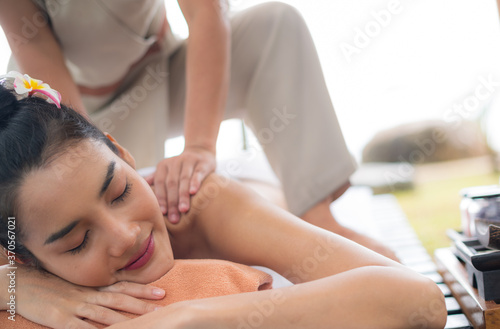 Asian young woman relaxing during back massage in the garden.