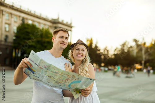 smiling couple in sunglasses with map in the city