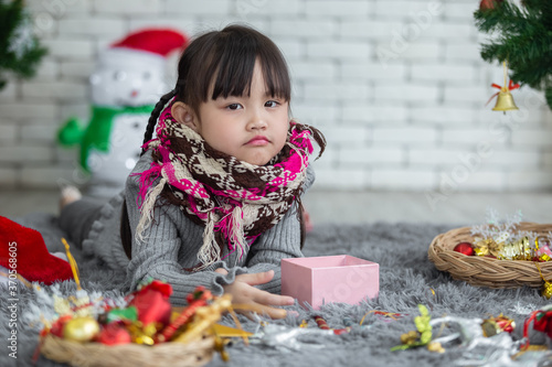 portrait of asian pretty beautiful little girl wear scarf lie leisurely in colorful christmas in winter.