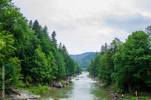 river in mountains. wonderful springtime scenery of carpathian countryside. blue green water among forest and rocky shore.sunny day with clouds on the sky © Tania