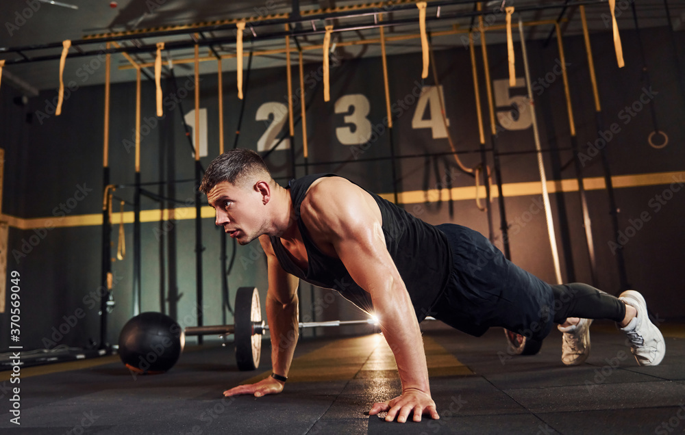 Fototapeta premium Strong man in sportive clothes doing push-ups in the gym