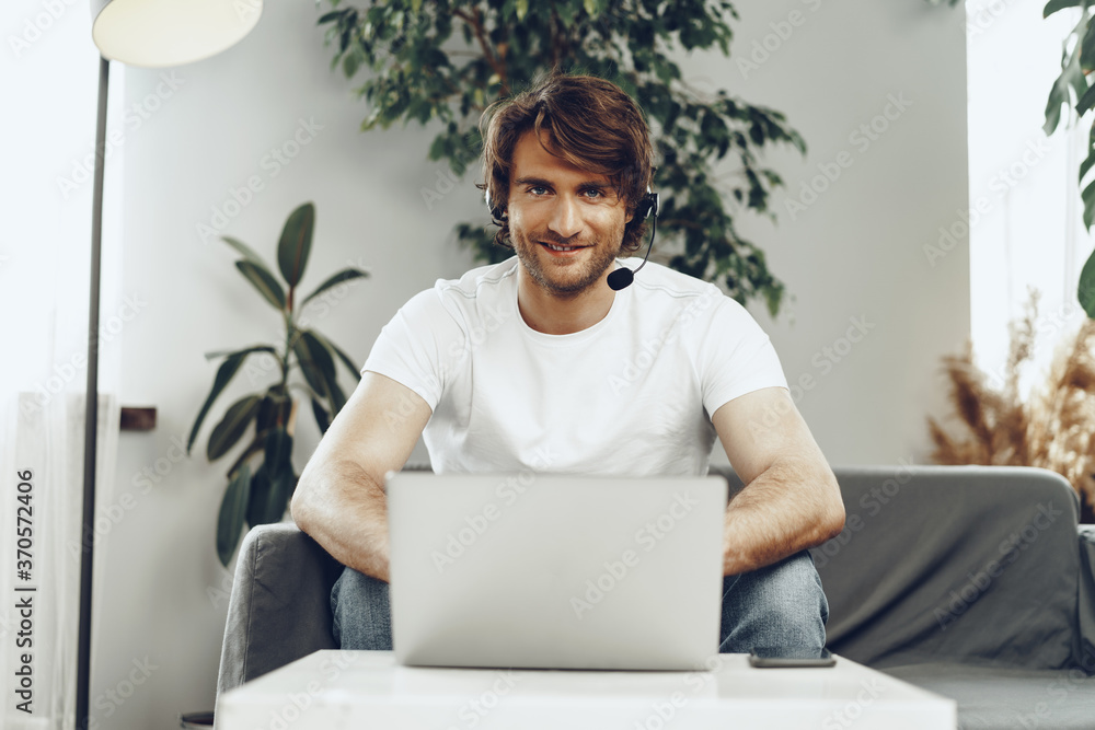 Young man businessman with headset working on laptop from home Young man businessman with headset working on laptop from home