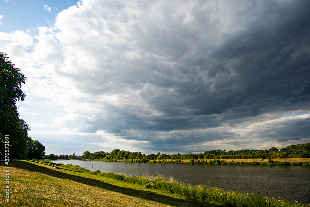 Obraz premium Beautiful cloudy and dark sky fighting the sun at Werdersee Bremen